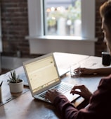 man operating laptop on top of table