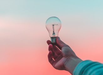 Hand holding glowing lightbulb against sky representing results-driven strategies