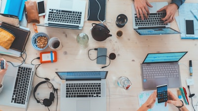 Top-down view of digital marketing team working on laptops, tablets and smartphones.