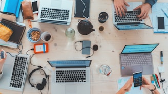 Top-down view of digital marketing team working on laptops, tablets and smartphones.