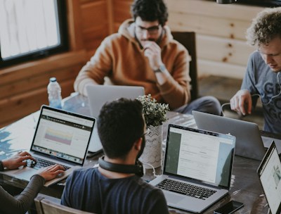 Men discussing marketing strategy with laptops and coffee in office