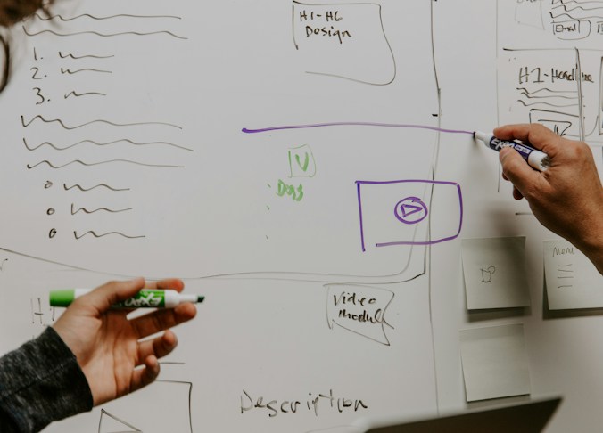 Two marketing professionals drawing strategy diagrams and notes on a whiteboard, illustrating lead g