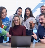 men and women sitting and standing while staring at laptop
