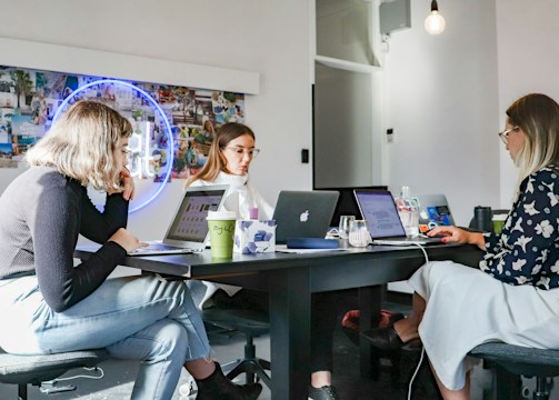 Women collaborating on laptops around a table for omni-channel marketing solutions