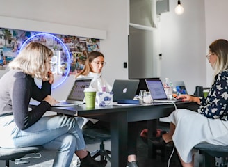 Women collaborating on laptops around a table for omni-channel marketing solutions