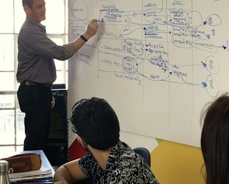A confident marketing leader facilitating a team meeting with clear KPIs displayed on a screen.
